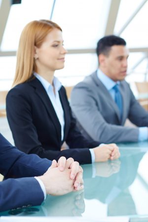 Row of business people listening to presentation at seminar with focus on elegant young man